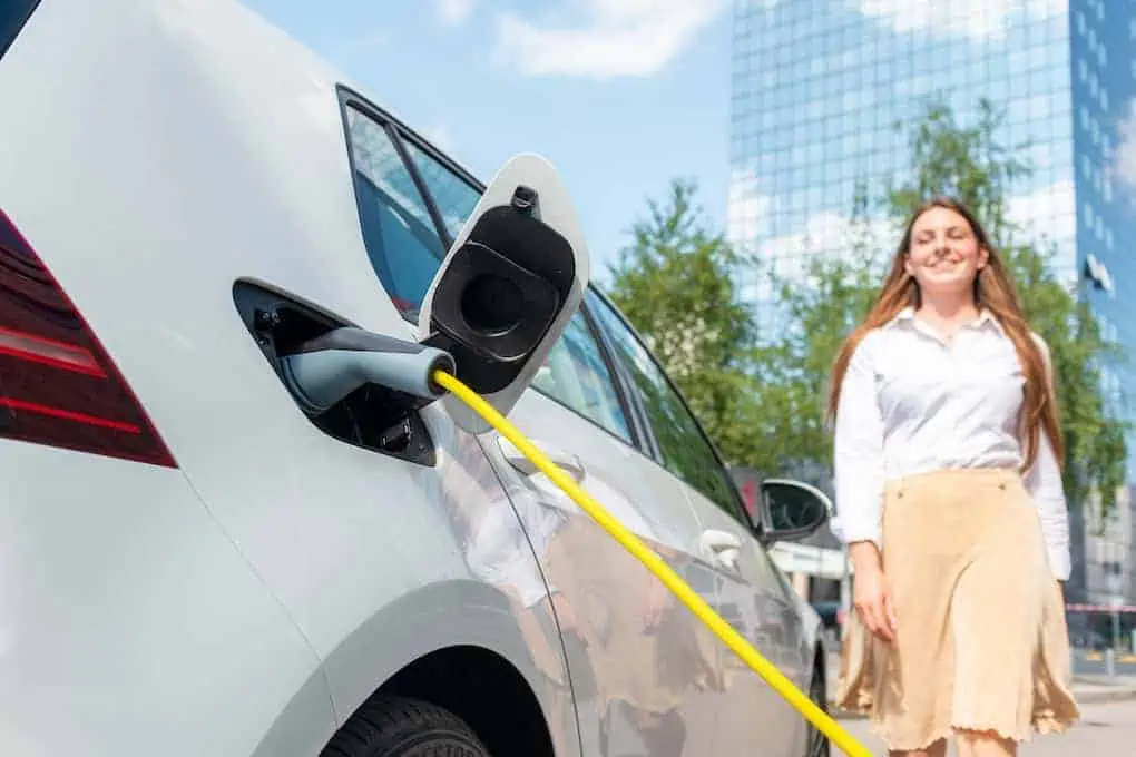 woman standing outside of electric vehicle; hotels with ev charging