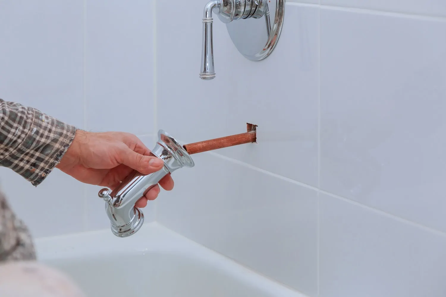 person installing bathroom tub faucet