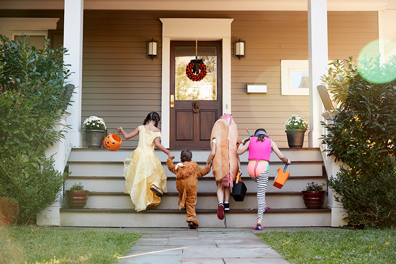 Four kids climbing up porch stairs in halloween costumes