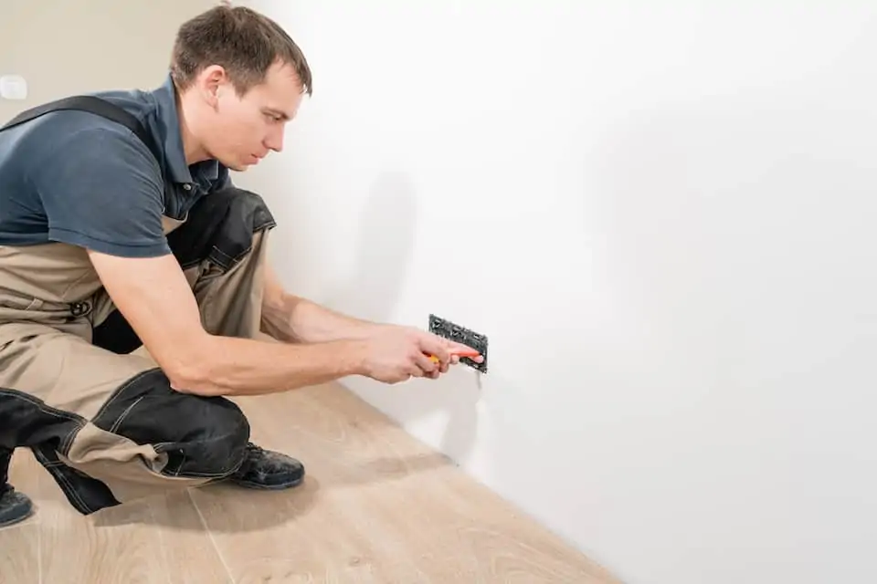 A young electrician installing an electrical socket in a new house; how to add an electrical outlet