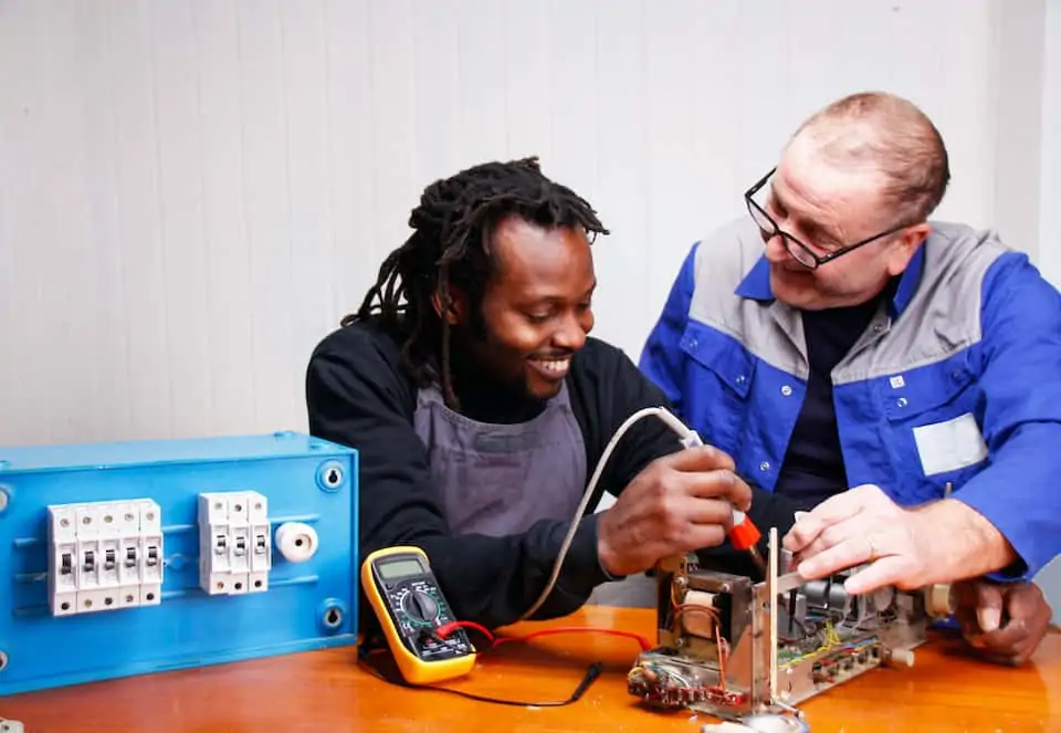 An experienced teacher teaching a young Electrician in the Workshop; how to become an electrician