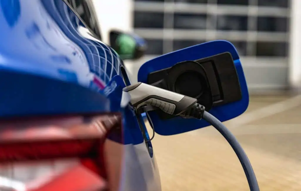 An EV charger is attached to a blue electric vehicle.