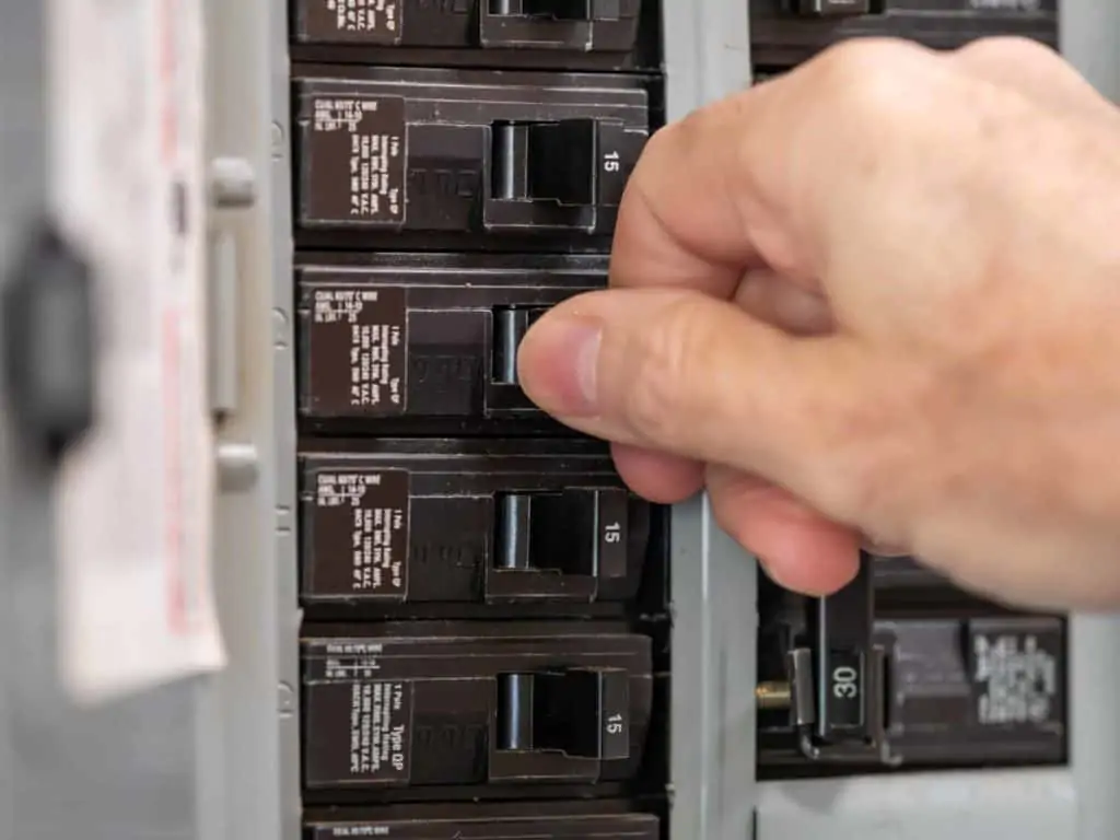 hand turning off circuit breaker to install a diy outlet