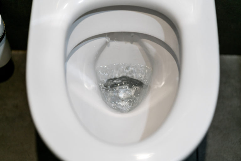 Toilet bowl flushing water in bathroom close up