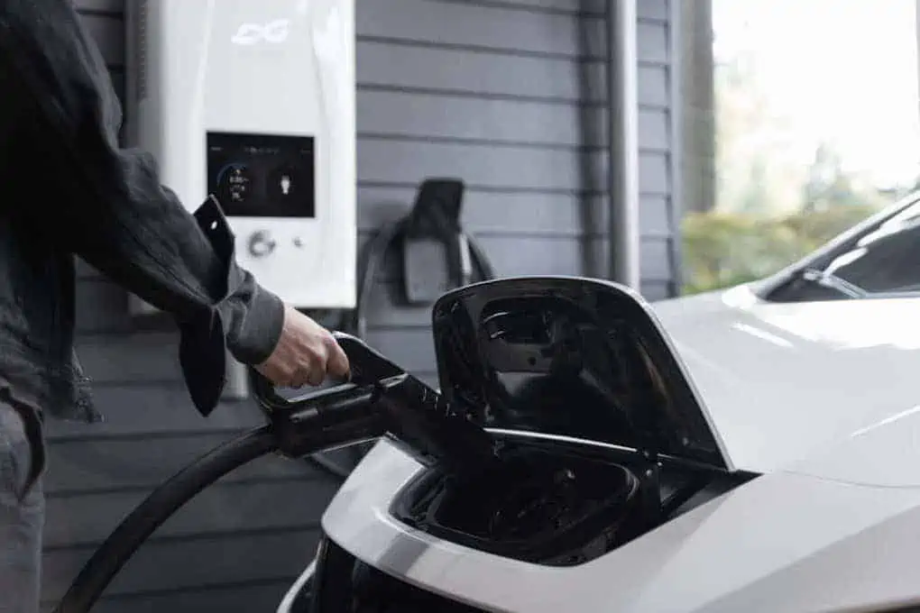 woman plugging in electric car in her garage; how long does it take to charge an electric car