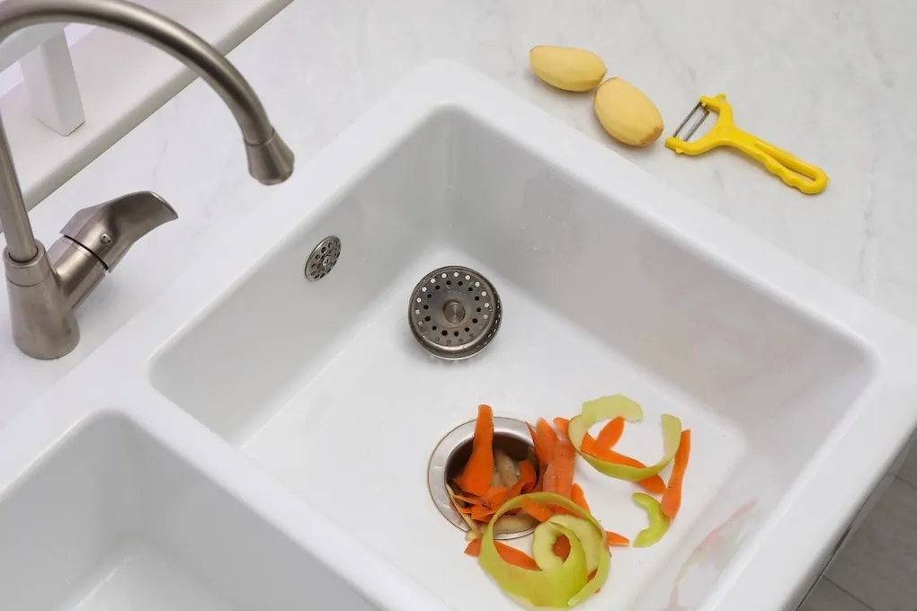above view of vegetables in white kitchen sink; how to install a garbage disposal