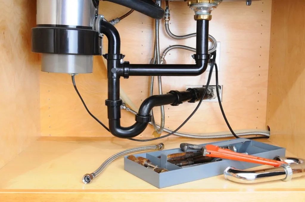 Detail of the plumbing system under a modern kitchen sink; showing how to install a garbage disposal