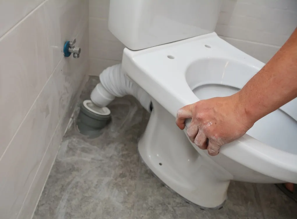 man showing how to install a toilet in bathroom