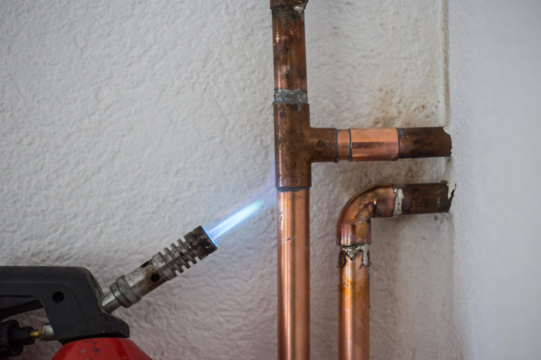 man heating the joints of pipes to sweat copper pipes together