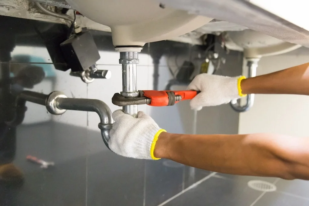 Plumber fixing white sink pipe with adjustable wrench; minnesota plumbing code