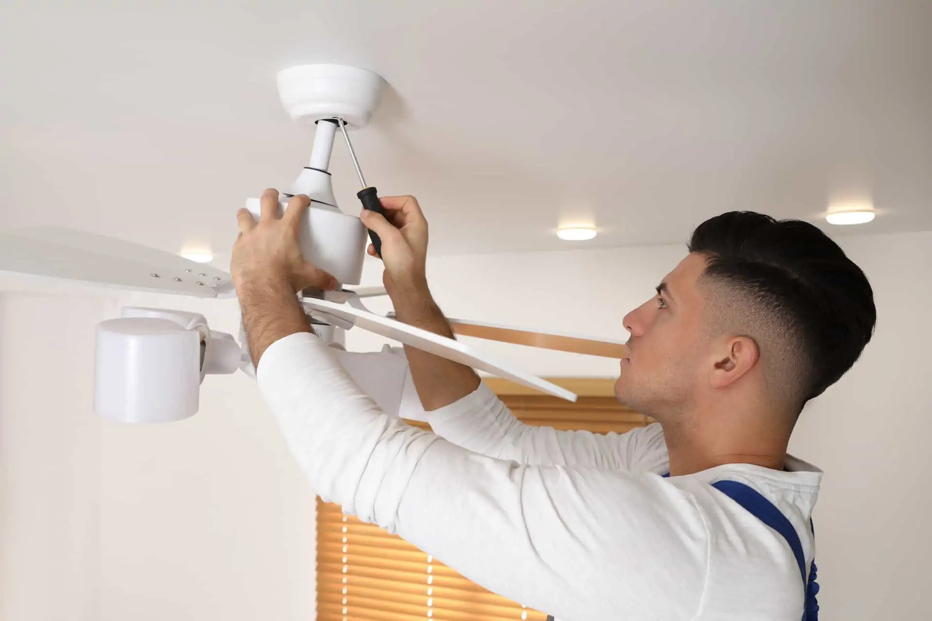 man installing a ceiling fan at home; how to install a ceiling fan