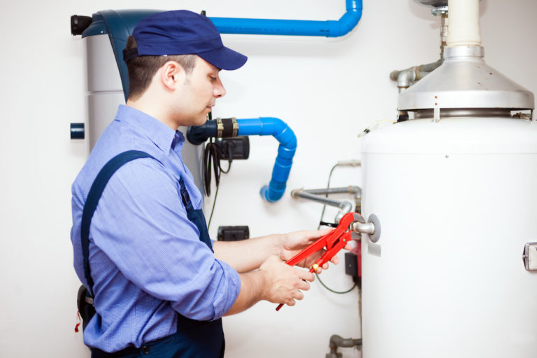 plumber fixing hot water heater; tankless water heater vs tank