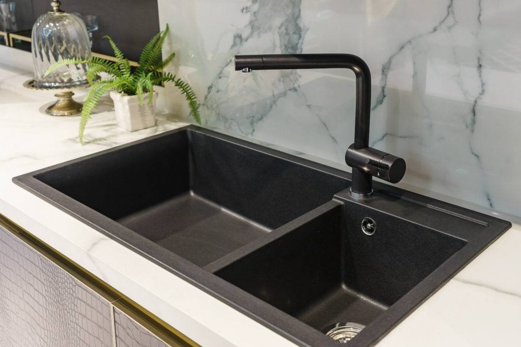 types of kitchen sinks - top mount sink with black against a cream colored countertop