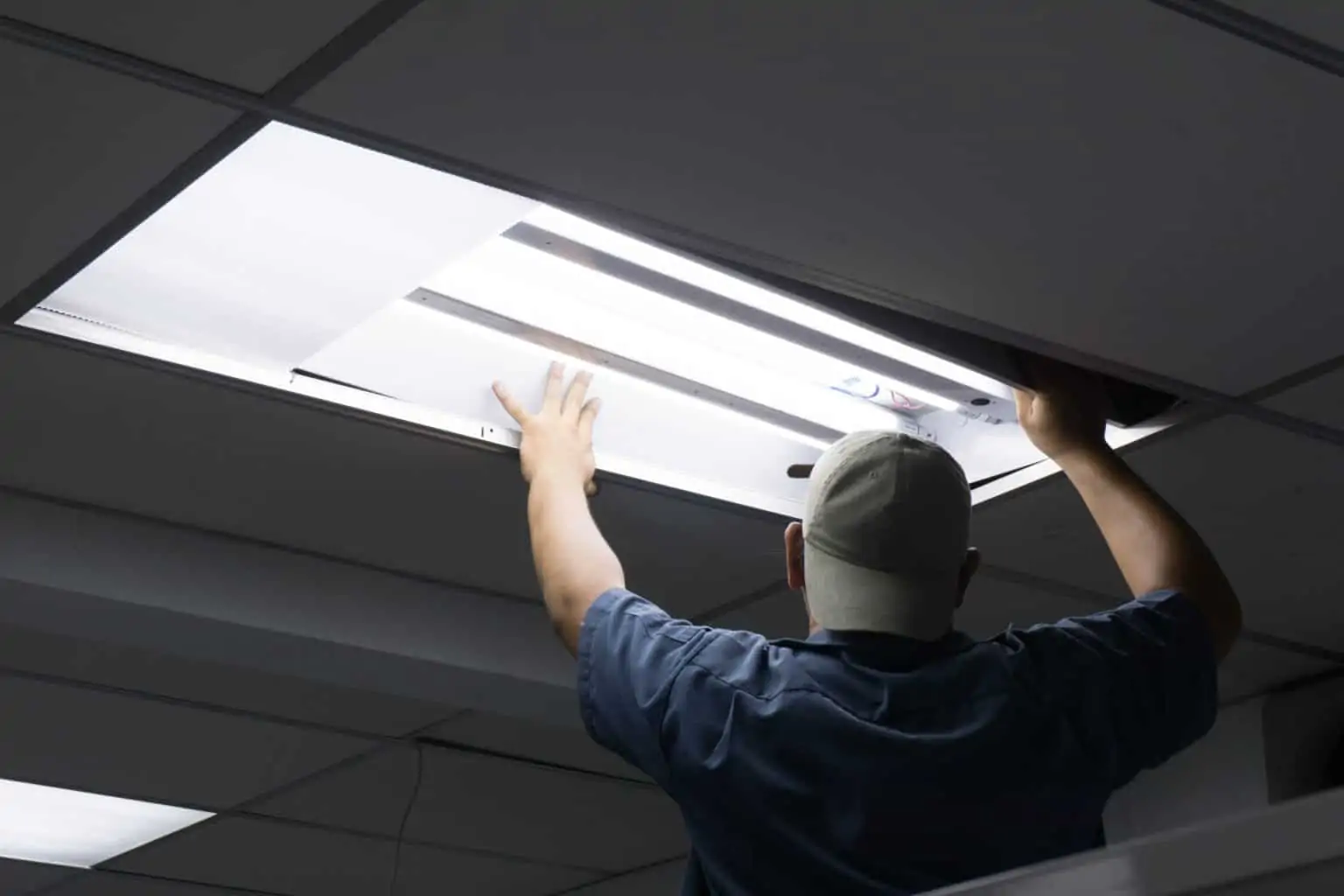 An electrician replacing overhead lighting