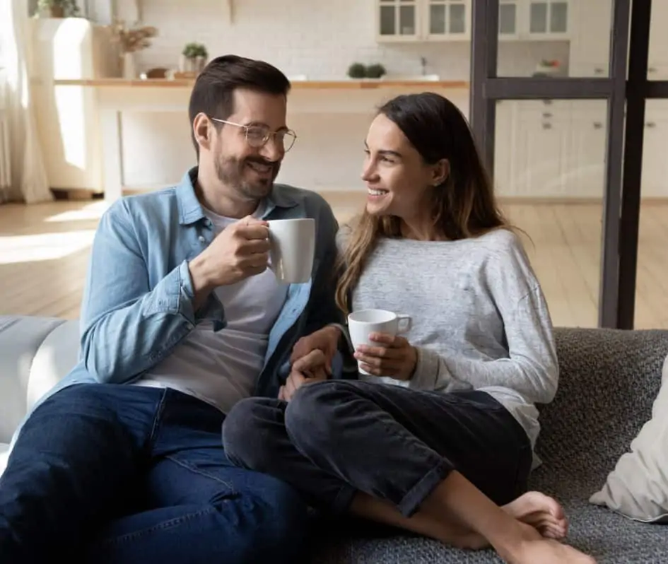 A smiling couple drinking coffee in their home