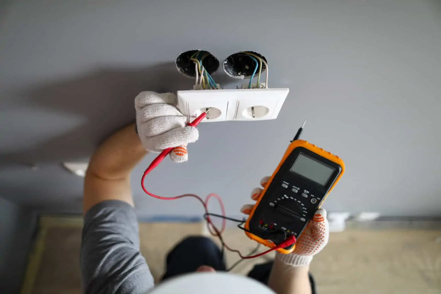 An electrician installing and testing a wall outlet