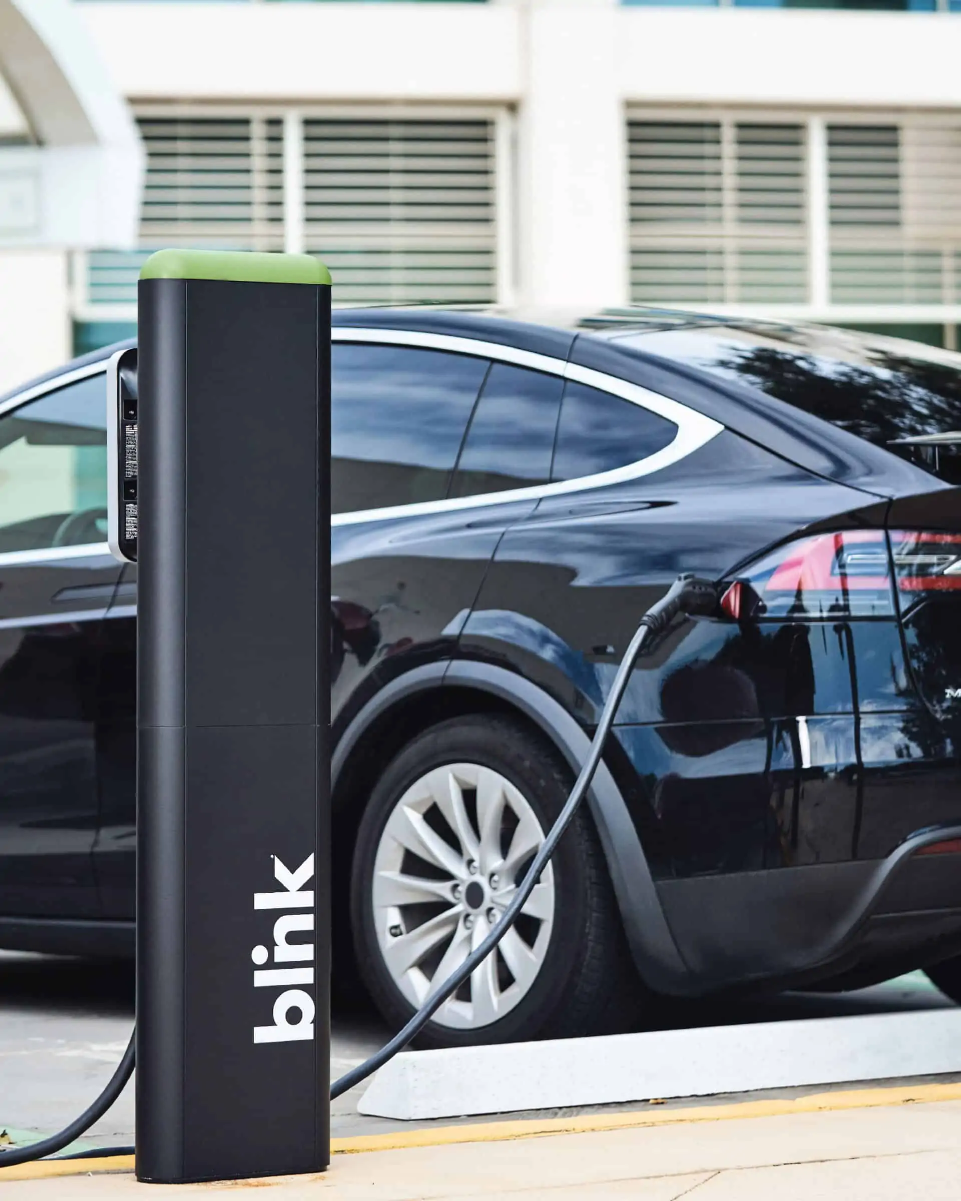 A black electrical car being charged by Blink Charging Station