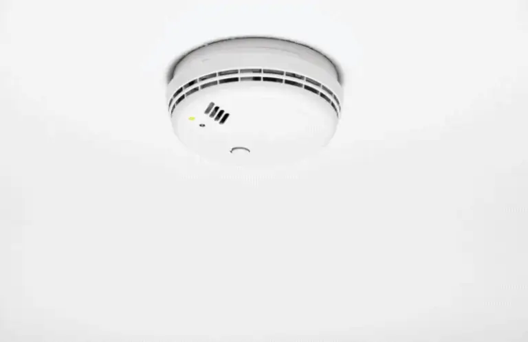 White smoke detector fitted on a white ceiling.