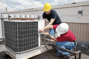 Two electricians working with a rooftop AC unit