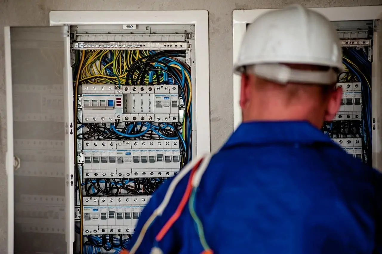 With their back turned away from the camera, an electrician works on an electrical panel.