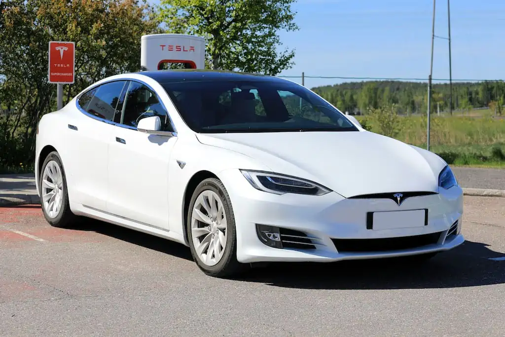 White Tesla model S charging at supercharger; extended range electric vehicle