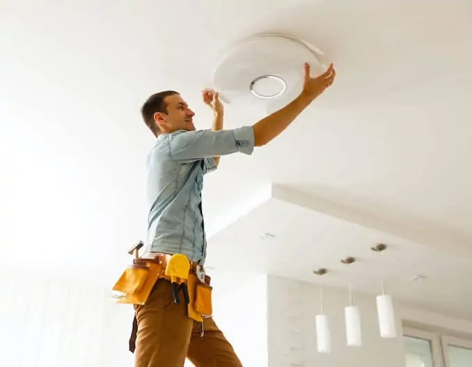 Electrician is installing and connecting a lamp to a ceiling; how to install a ceiling light