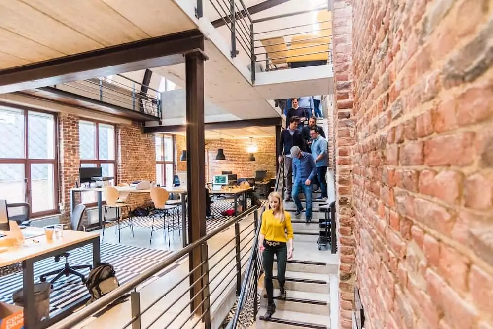 An open-concept brick office with people walking down the stairs