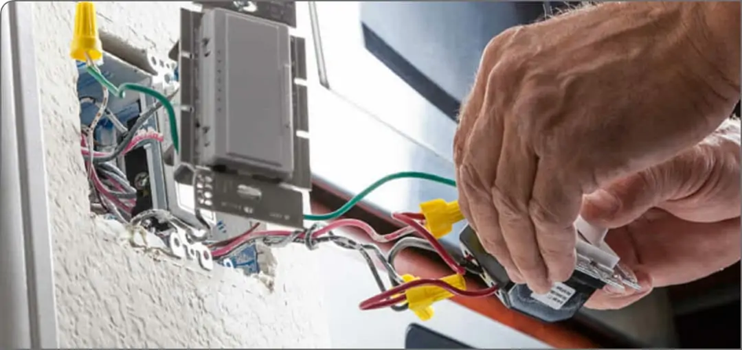 A close-up of an electrician's hands as they work with an outlet's wires