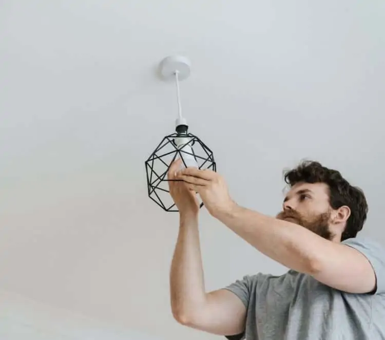 A man installing a lightbulb on an overhead light fixture
