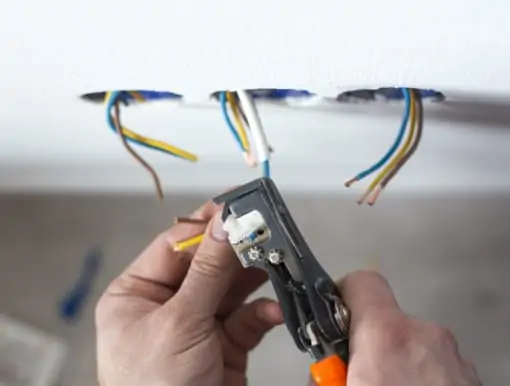 An electrician's hands as they work on wires with pliers
