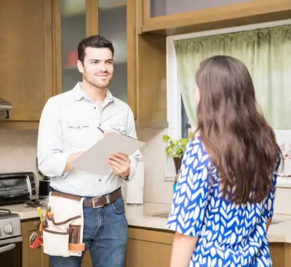 A smiling electrician speaking to a woman in a kitchen