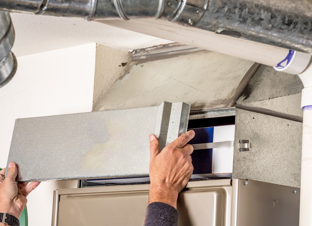 HVAC technician removing panel to access furnace filter