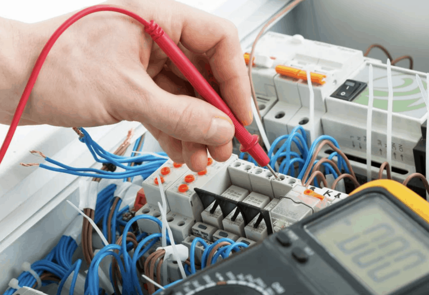 With only one hand visible, an electrician is testing voltage with a tool.