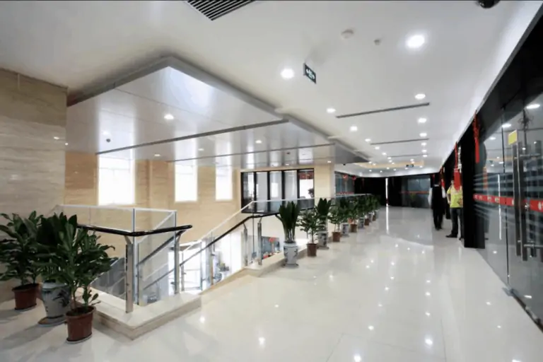 A commercial office building with bright white lights overhead & plants lining the glass railings.