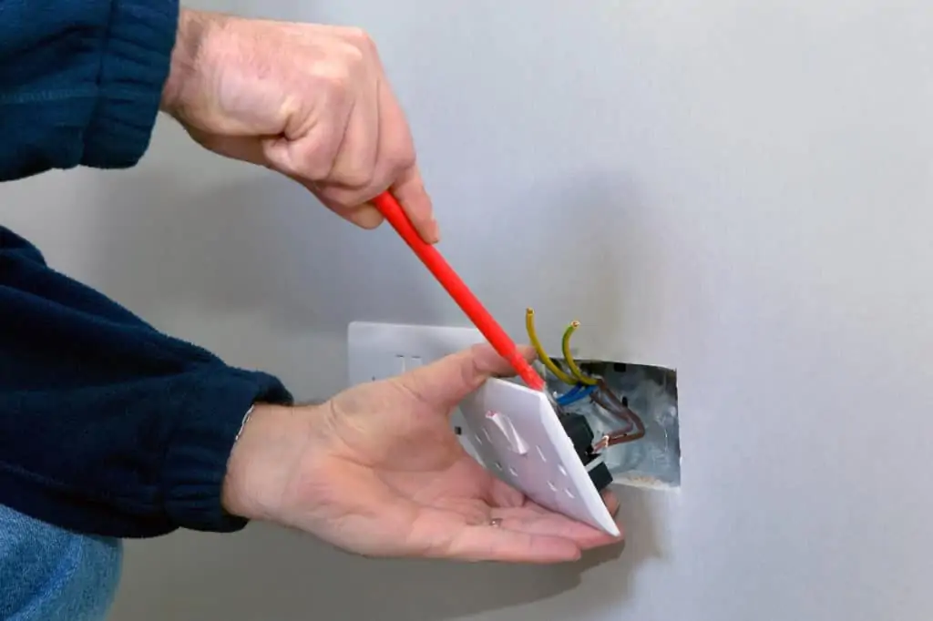 hands of a man working on an electrical socket