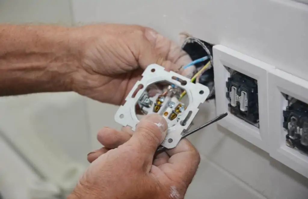 man feeding cable through his diy outlet 