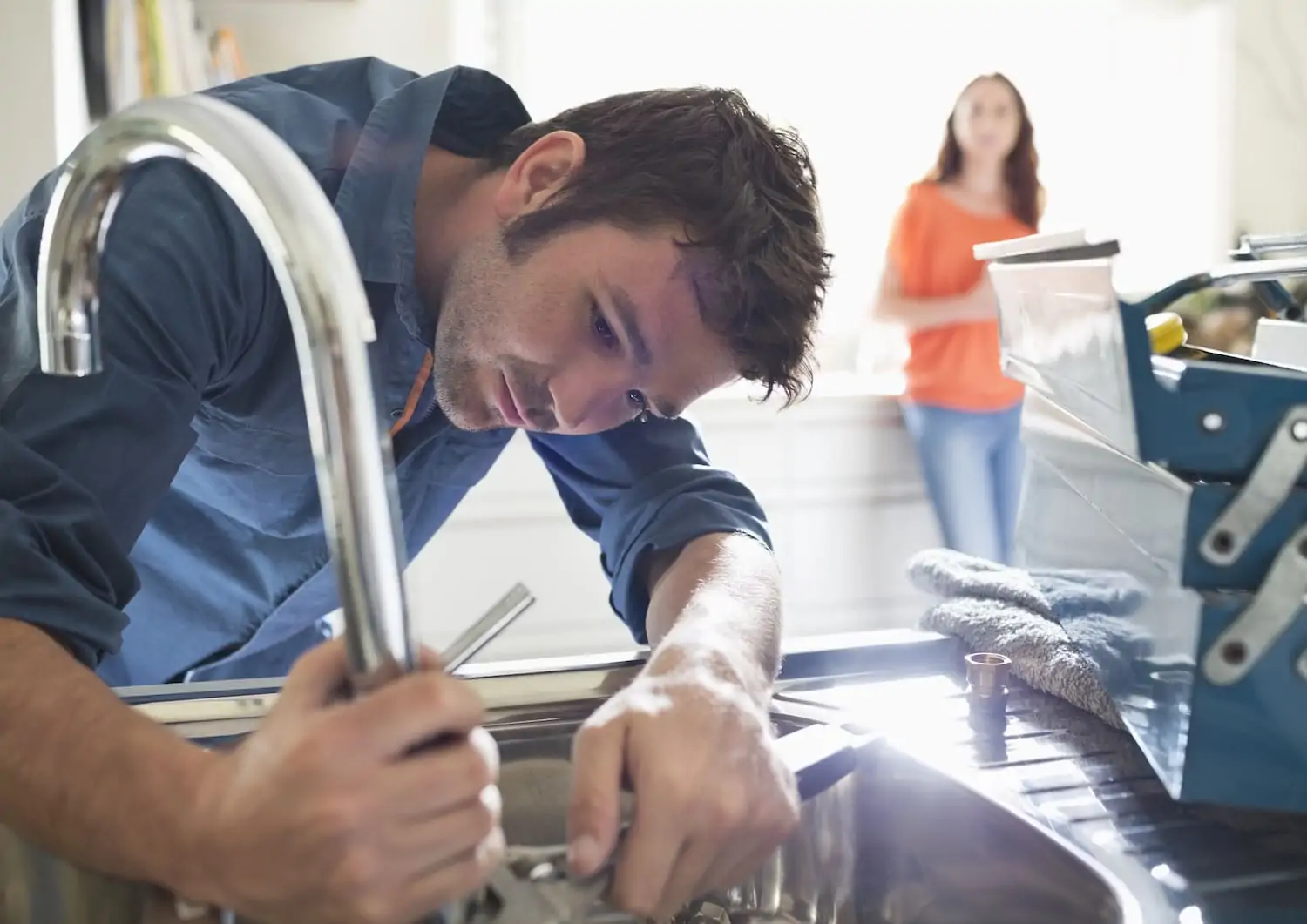 Plumber repairing a sink plumbing issue within the silver faucet