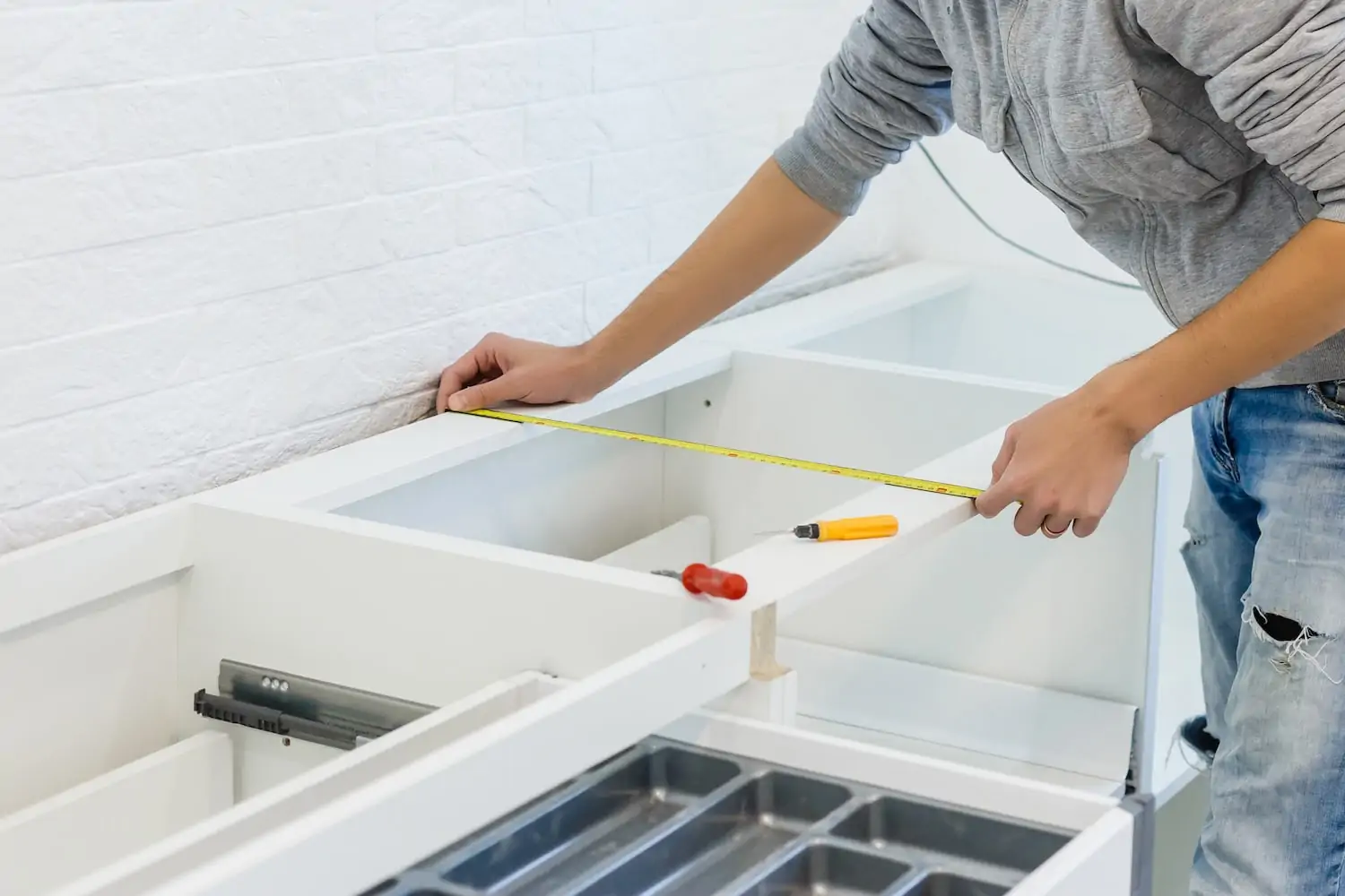 Worker measuring the width of white wood with a tape measure