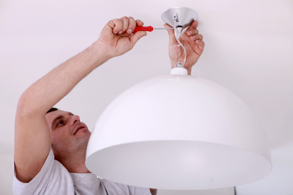 man fixing an electrical light fixture; diy electrical