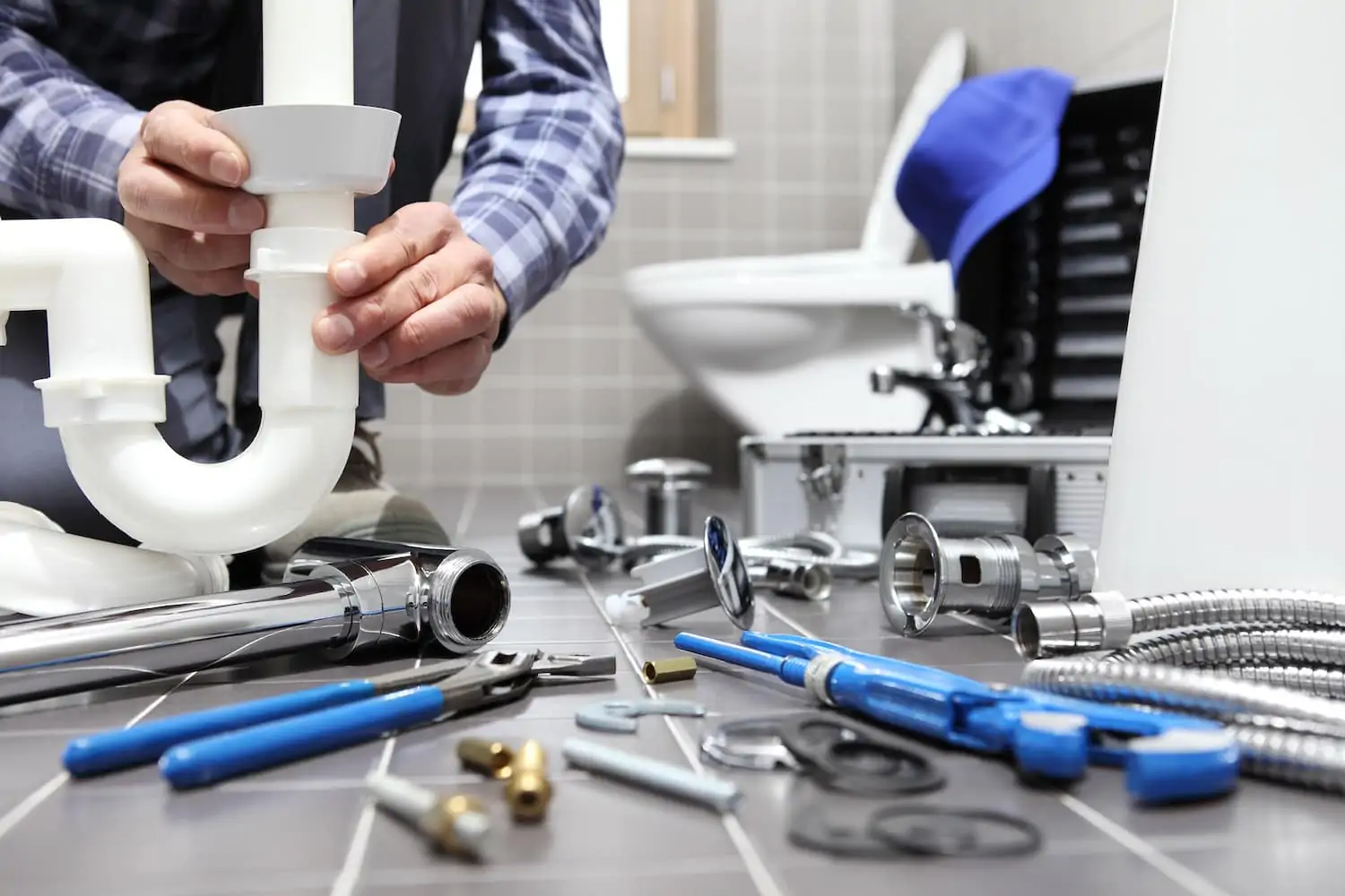 A plumber putting parts together for a new plumbing fixture with white pipes