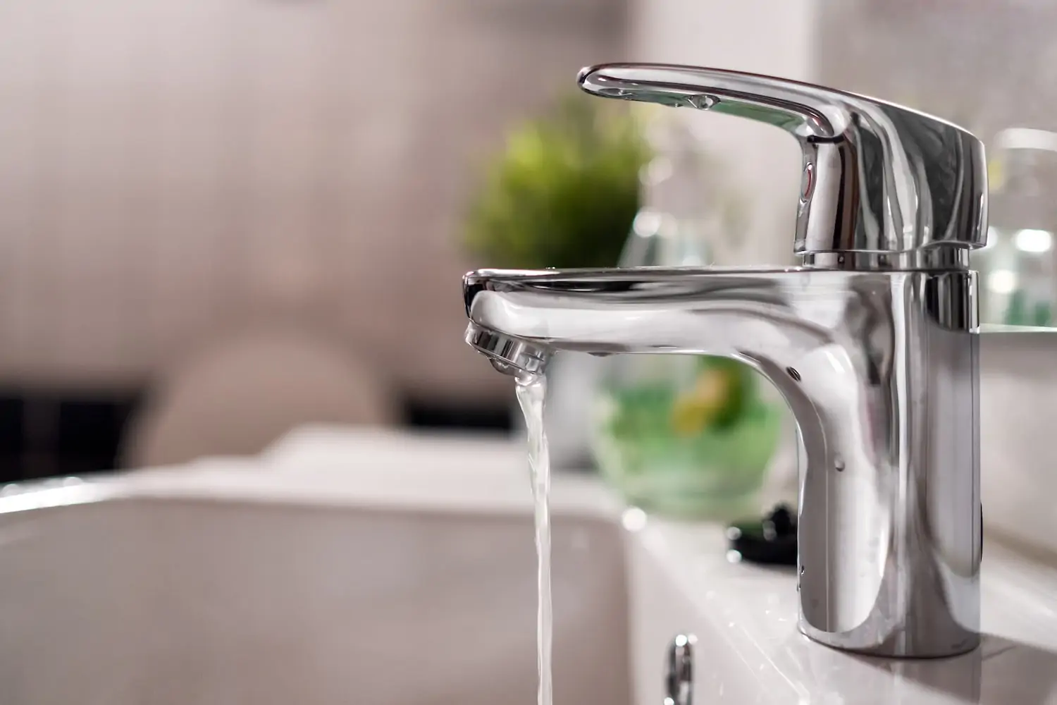 A silver faucet running water into a white sink