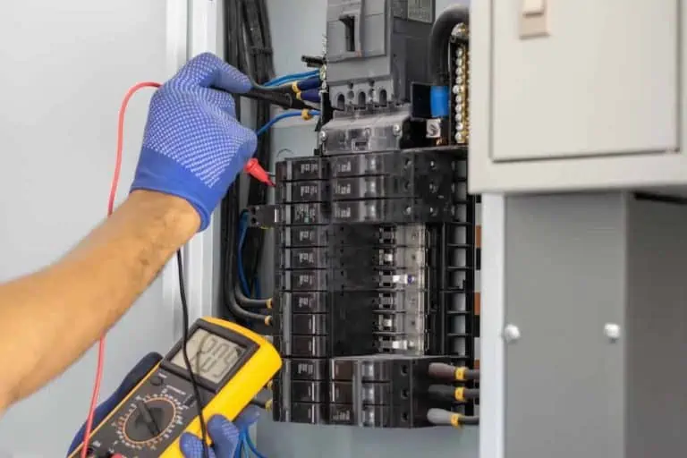 pair of hands testing wires inside electrical panel; things that fail a home inspection