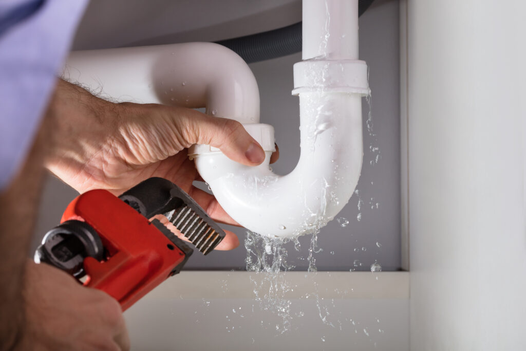 Plumber fixing a leak under a sink